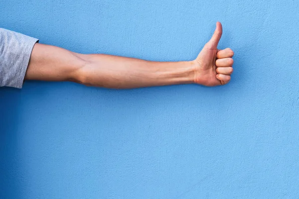 Gesture of approval and praise (Ok!). Thumbs up. Hand on a blue background with copy space