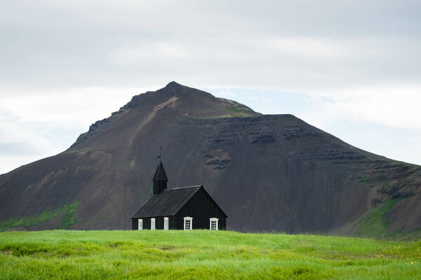 Budir church in Iceland. Black chapel on the background of the mountain. Summer Landscape. Religious and tourist attraction