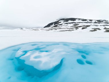 Buzlu turkuaz Gölü yakınındaki dağ yoluna Bjorgavegen. Bulutlu Kuzey manzara. Norveç manzaralı yoldan Aurlandsfjellet