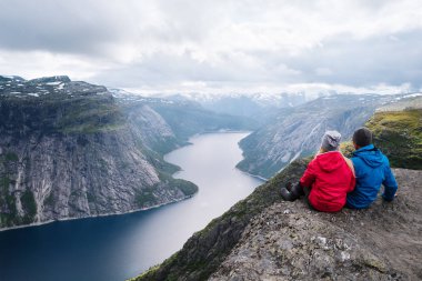 Ringedalsvatnet göl kenarında Trolltunga. Bir Norveç en muhteşem manzara. Çift yolcuları kayanın üzerinde oturur ve güzel bir manzaraya sahiptir