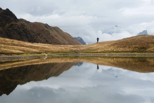 Mountain lake with a mirror reflection of clouds. View of Main Caucasian ridge. Tourist enjoys the picturesque scenery. Koruldi, Samegrelo-zemo svaneti, Georgia