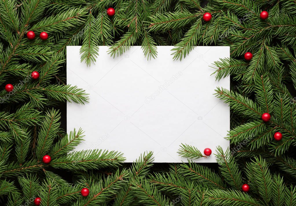 Christmas card background. Paper notice sheet with copy space for text.  Decorative frame of fir branches and holly berries. Flat lay, top view