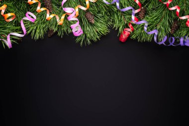 Çam dalları ve siyah bir zemin üzerine şenlikli flamalar ile Noel sınır