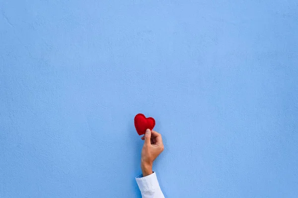 青い壁の背景に男の手に赤いバレンタインの心 コピーのテキストのための領域とグリーティング カード — ストック写真