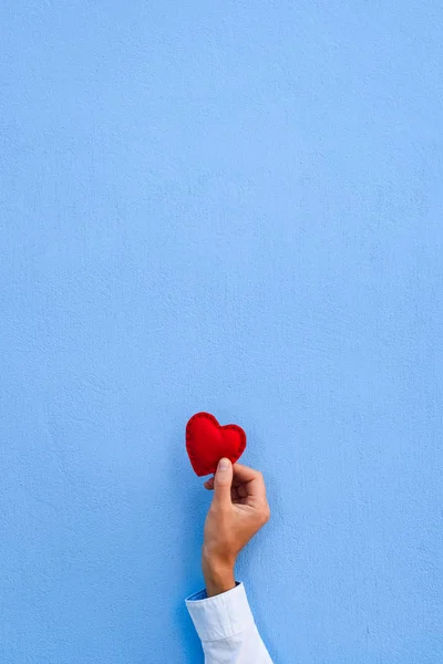 青い壁の背景に男の手に赤いハート あいさつ文のコピー スペースとバレンタイン カード 中央対称構成 — ストック写真