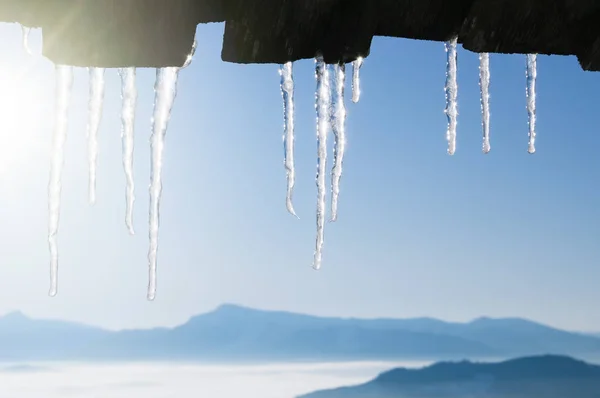 つららの境界線と冬の背景 青い空と山のピークを持つ天気 — ストック写真