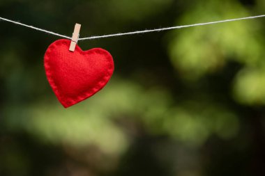 Kırmızı kalp üzerinde arka plan bulanık bir clothespin ile bağlı. Sevgililer günü kavramı ile metin reklam için kopya alanı