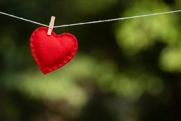 Kırmızı Kalp Üzerinde Arka Plan Bulanık Bir Clothespin Ile Bağlı — Stok fotoğraf