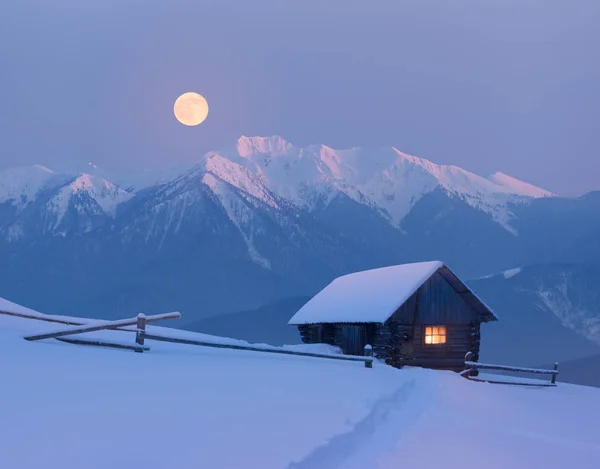 Christmas landscape with a snowy house in the mountains on a moo — ストック写真