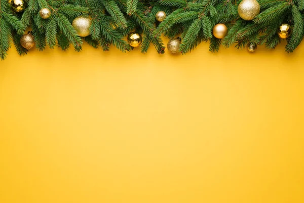 Natal fundo amarelo com borda de abeto e decoração — Fotografia de Stock