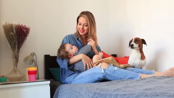 眠そうな息子と犬とベッドの上に座っている女性 — ストック動画