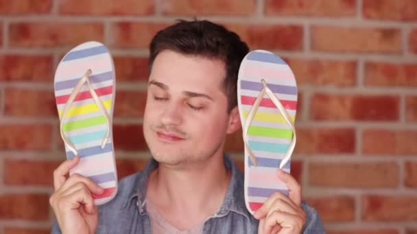 Hombre Mostrando Chanclas Arco Iris Sobre Fondo Pared Ladrillo — Video de stock gratis