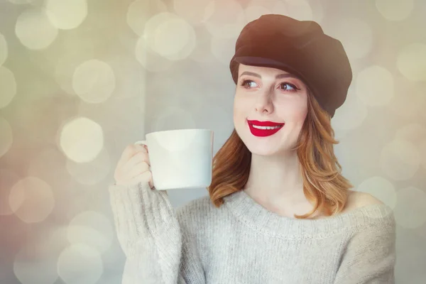 Kvinna i tröja och mössa med kopp kaffe eller te — Stockfoto