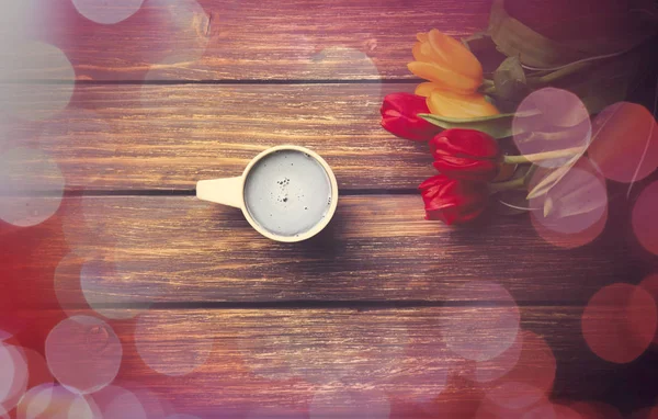 Taza de café y tulipanes sobre mesa de madera . —  Fotos de Stock