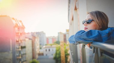 kız kot elbise ve balkonda güneş gözlüğü