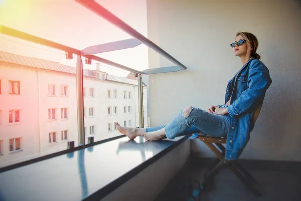 Fille en jeans vêtements et lunettes de soleil sur le balcon — Photo