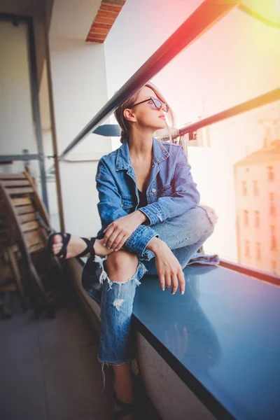 Girl in jeans clothes and sunglasses on balcony — Stock Photo, Image