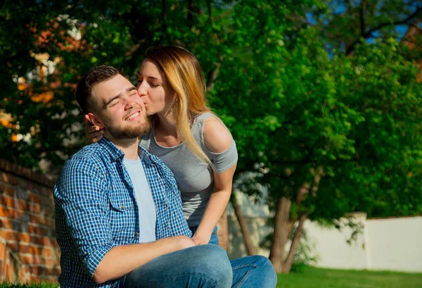 Pareja joven sentada sobre una hierba verde — Foto de Stock