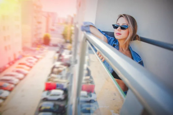 Κορίτσι σε ρούχα τζιν και γυαλιά ηλίου στο μπαλκόνι — Φωτογραφία Αρχείου