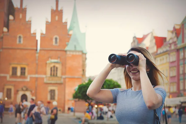 Girl looking through binoculars at a city — Stock Photo, Image