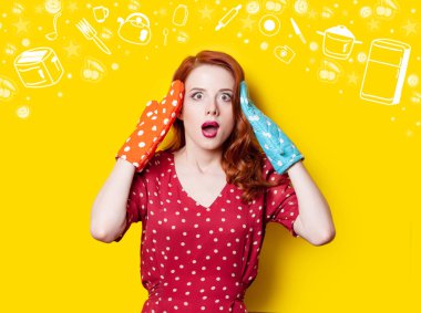 Sürpriz Kızıl saçlı kız kırmızı puantiyeli elbise ve eldivenler ve sarı zemin üzerine çizilmiş mutfak eşyaları.