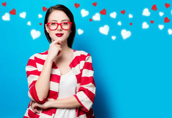 Joven mujer sonriente sobre el fondo azul con corazones — Foto de Stock