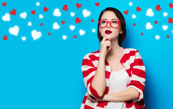 Joven mujer sonriente sobre el fondo azul con corazones — Foto de Stock