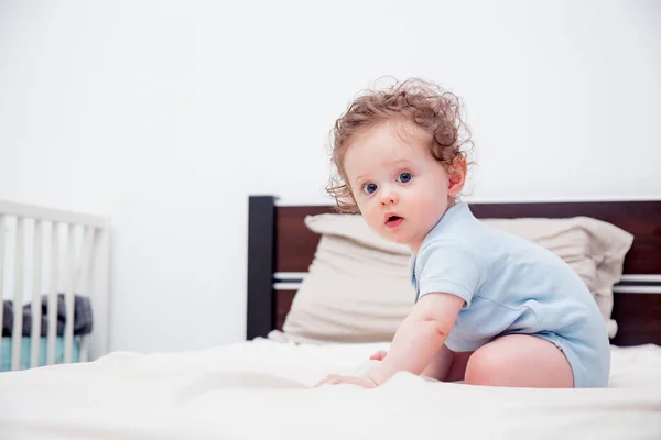 Göndör baba kisfiú ült egy ágyon — Stock Fotó