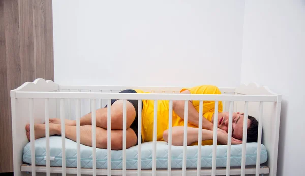 Tired father sleep in a child cot — Stock Photo, Image