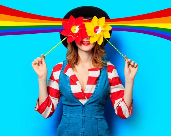 Mujer sonriente con dos molinetes y arco iris — Foto de Stock