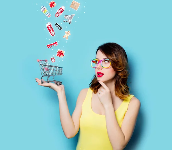 Mujer joven con carrito de compras y con ropa — Foto de Stock