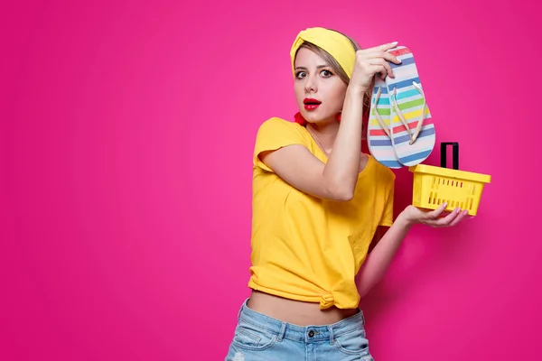 Girl holding flip flops and supermarket basket — Stock Photo, Image
