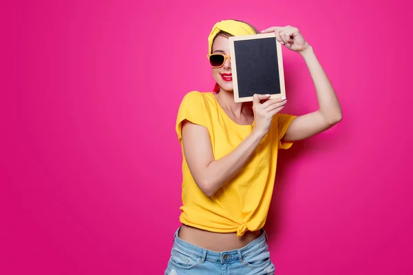 Menina em camiseta amarela com pouco quadro negro — Fotografia de Stock