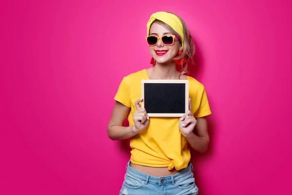 Meisje in het geel t-shirt met kleine blackboard — Stockfoto