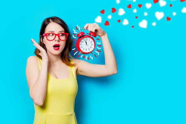 Young woman with alarm clock and abstract hearts — Stock Photo, Image