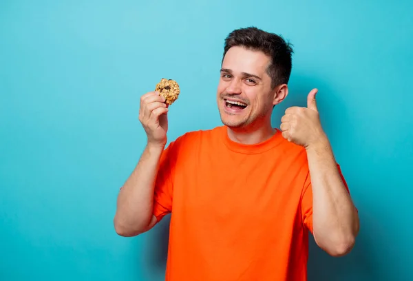 Молодий красивий чоловік в помаранчевій футболці з печивом . — стокове фото
