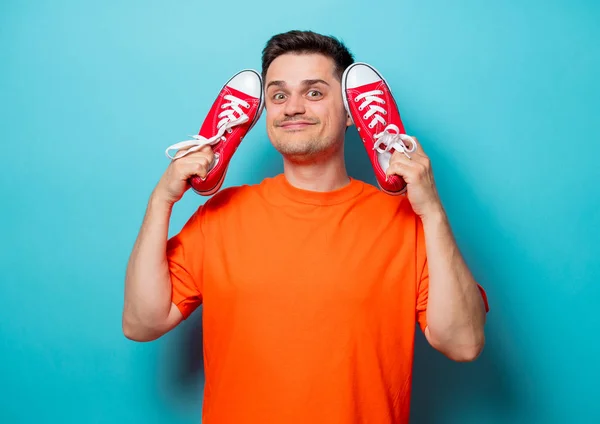Красивый мужчина в оранжевой футболке с красными резиновыми туфлями — стоковое фото