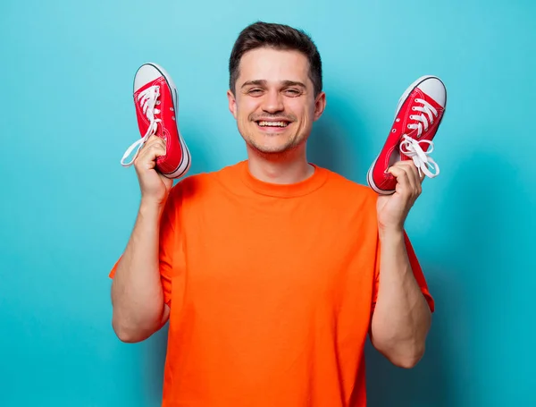 Knappe man in oranje t-shirt met rode gumshoes — Stockfoto