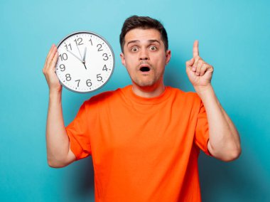 büyük saat ile turuncu tişört erkekte