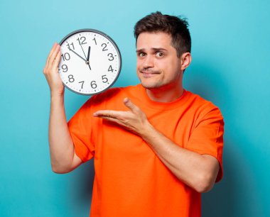 büyük saat ile turuncu tişört erkekte