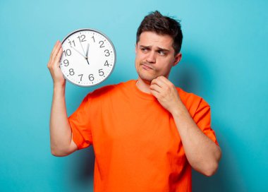 büyük saat ile turuncu tişört erkekte