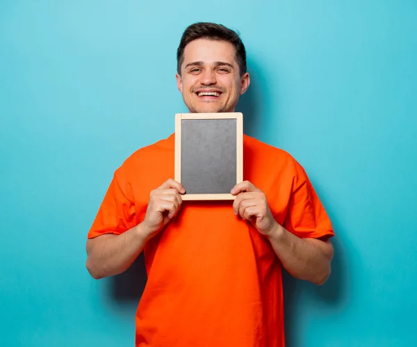 Man in oranje t-shirt met kleine blackboard — Stockfoto