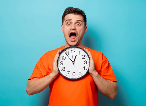 Man in oranje t-shirt met grote klok — Stockfoto