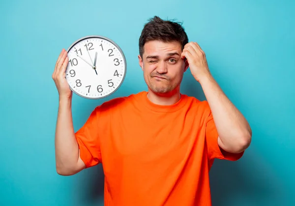 Man in oranje t-shirt met grote klok — Stockfoto