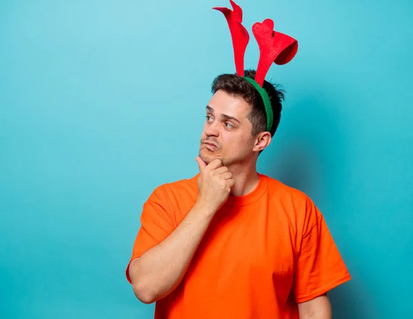 Мужчина в оранжевой футболке с рождественскими оленьими рогами — стоковое фото