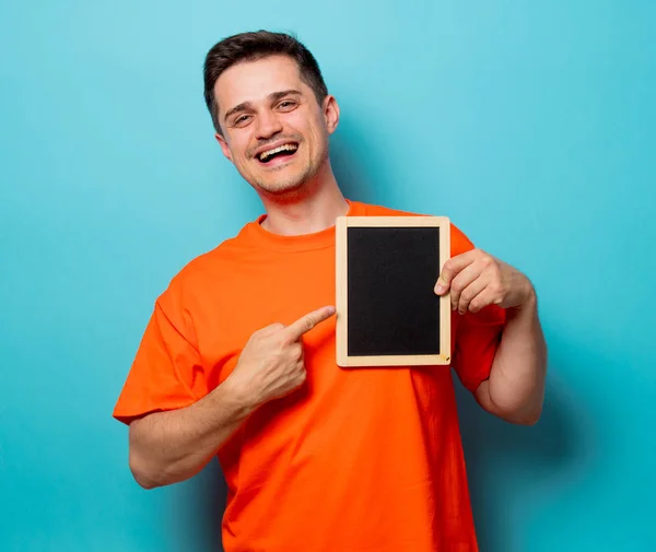 Man in oranje t-shirt met kleine blackboard — Stockfoto