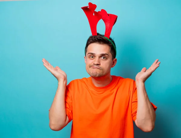 Man in orange t-shirt with Christmas deer horns — Stock Photo, Image