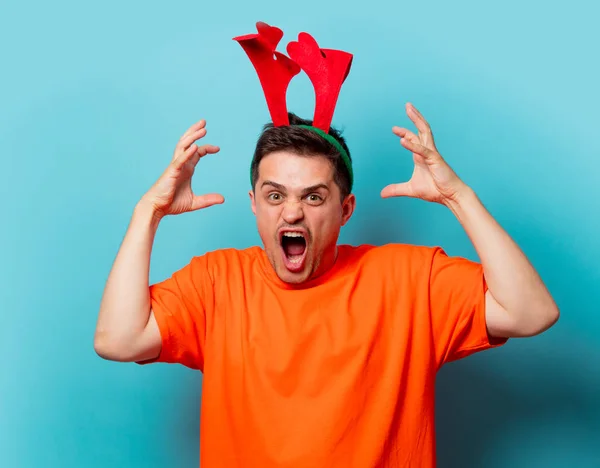 Homem em camiseta laranja com chifres de veado de Natal — Fotografia de Stock