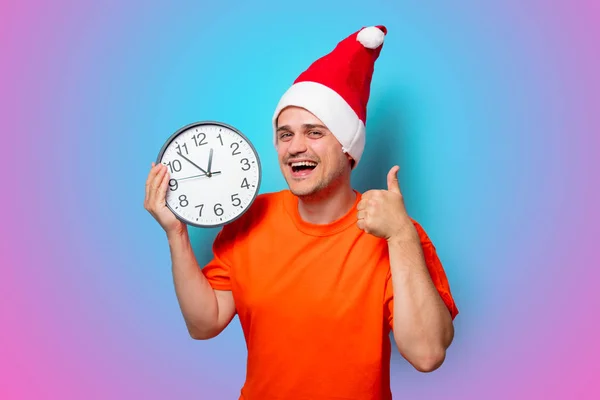 Homme avec chapeau de Noël et grande horloge — Photo