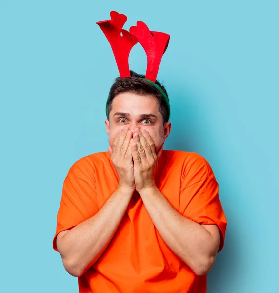 Man in orange t-shirt with Christmas deer horns — Stock Photo, Image